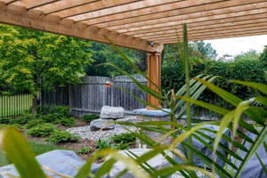 A photo of a backyard pergola with natural rock landscaping.